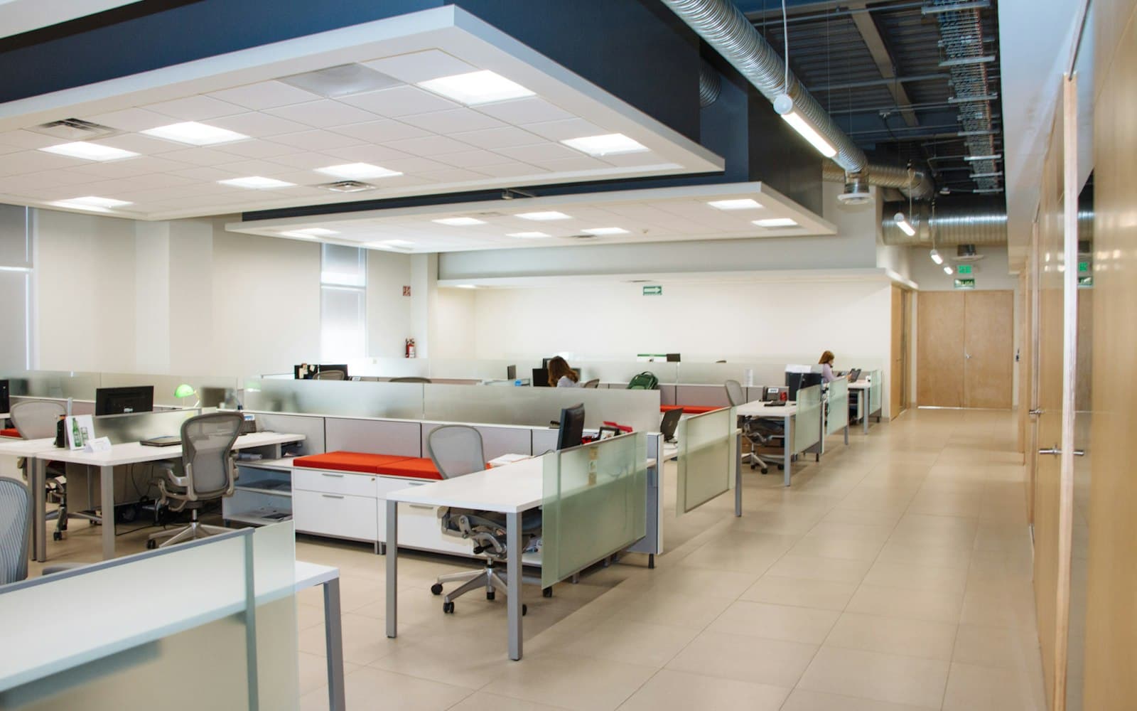 An open-plan office with rows of white desks.